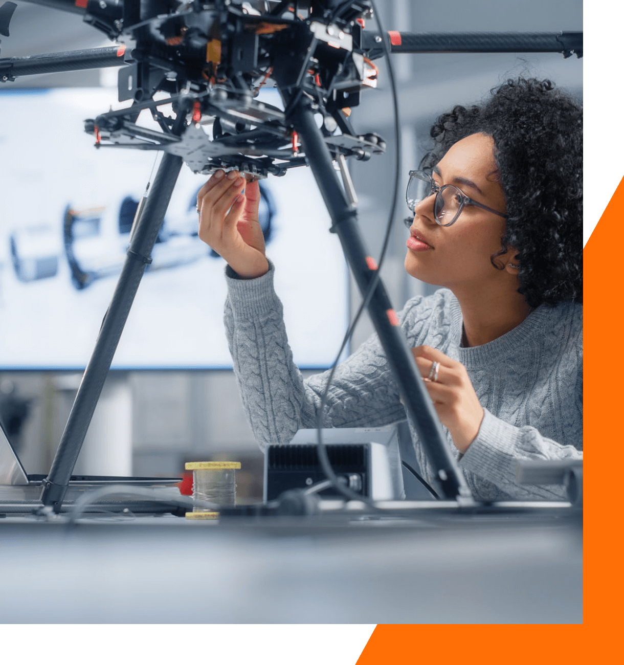 Woman examining drone in a lab setting.